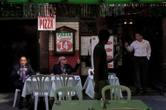 Little Italy  -  Savatore Rinaldi, center, a co-owner of the Paesano restaurant on Mulberry, talks to a waiter while with his friend  Dimitri Vassilopoulos during the start of the Feast of San Gennaro in the Little Italy neighborhood of Manhattan. The 11 day food and culture festival is one of NYC’s biggest. Saturday 09 17 2022  New York, NY.
