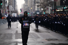 A man walks with the photo of Police officer William Rivera who was shot to death with his partner Police Officer Wilbert Mora in Harlem, just before the funeral at St. Patrick’s Cathedral Jan 28. 2022.