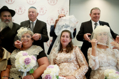 Grooms adjust their brides veils to start the wedding ceremony. Six couples who had a civil marriage in Russia or the Ukraine but could not have a religious wedding that followed Jewish traditions/ceremony/law, were wed, at the same time, by six rabbi’s, in Parsippany, N.J. September, 18, 2022