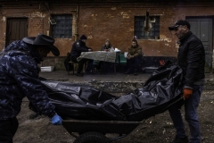 During an interview with authorities, Svetlana Kostyantyn and her son, Sergii, watch in shock as the body of her husband and father, Kostrya, is exhumed from a makeshift grave in the backyard of the family’s home and taken for examination in Bucha, Ukraine, on 4.19.22. Russian soldiers shot Kostrya and his brother as they walked in a nearby park. Svetlana had to go to the Russian soldiers and ask them to let her bury her husband. They denied her multiple times before they relented and let her take Kostrya home but made her leave the corpse of her brother-in-law in the park, where it would take days or weeks for Ukrainian authorities to discover.