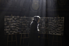 A woman prays as she walks past a bulletin board showing portraits of those killed by invading Russian forces in Lviv, Ukraine, on 3.18.22. This board reflects the lives lost in the first month of the war. Almost a year later, countless families have been ripped apart by violence and death - the only reliable promises of war. Yet, the Ukrainians remain hopeful and resilient against all odds.