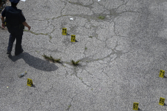 A police officer walks near evidence markers at the scene of a deadly mass shooting in Harlem  on June 20, 2022.