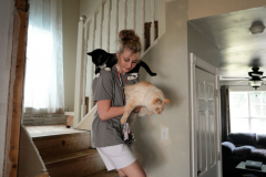 Eden Hoeffling, 17, walks down the stairs at home carrying her cats Figgy (black) and Snowball, in Sedalia, Mo., on September 24, 2023. Due to her disorder, Hypogammaglobulinemia, Eden is hoping to get Figgy registered as an Emotional Support Animal to take her with her to college.
