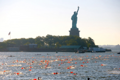 JERSEY CITY, NJ USA - AUGUST 19, 2023 -  Swimmers go to a barge past the Statue of Liberty while swimming in the Hudson River. They would later swim to NYC and end the day visiting the 9/11 Memorial Pools.