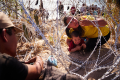 Honduran mother crawls through razor wire with three children