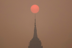 JERSEY CITY, NJ - JUNE 6: The sun is shrouded by forest fire smoke from Canada as it rises in a  sky behind the Empire State Building in New York City on June 6, 2023, as seen from Jersey City, New Jersey.