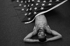 A person lies on the floor draped in an American flag at a protest concerning the death of Jordan Neely in Manhattan, New York. 06 May 2023.