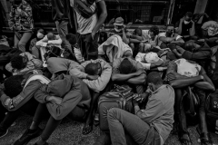 August 2, 2023.  Migrant men line outside the Roosevelt Hotel in New York City. Migrants are allowed to leave but they stay to keep their place in line, to get food.  There was confusion and a language barrier. Families get priority for shelter and processing. Men wait outside.  NYC officials have said the city is running out of room to house the migrants, expected to cost the city 12 billion next three years.