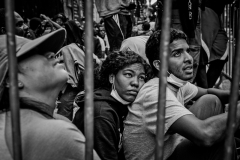 August 1, 2023  Migrants sit behind a barricade outside the Roosevelt Hotel. There were no awnings to protect them from the blazing sun during the day. Migrants can leave but they say to keep their place in line and to get food. Women and children get priority in processing and shelter but not couples.