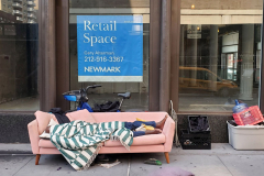 New York, New York   August 2, 2024 Homeless man sleeping on a couch on a side walk in from to a vacant storefront on Broadway in  Manhattan.