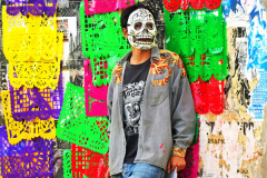 A Day of the Dead reveler in Oaxaca, Mexico  with a typical skull painted face-watches the festivities. The skull  or -the calavera (a word that means “skull” in Spanish) has become one of the most recognizable cultural and artistic elements of the Day of the Dead.. October 31, 2024.