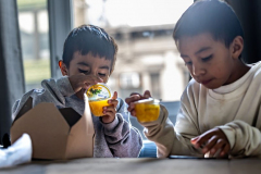 Migrant Julio Zambrano, with his two sons Julio, 9, and Joseph, 6, arrived at Canal Loft a hotel in Chinatown in New York City, Thursday, Jan. 4, 2024 after a long 2 months journey from Guatemala.  Joseph left could not wait to eat with is brother Julio after arriving at the hotel.