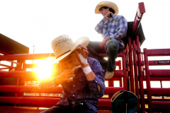 The Cowtown Rodeo is the oldest weekly rodeo in the country, with five thousand people watching every Saturday night from May through October. It is located in Southern NJ and draws professional cowboys from all over the country. Fans drive for hours to see the competition and it is the biggest social gathering on a Saturday night in the area. The sixth generation of the Grissom family now helps run the rodeo. PILESGROVE, NJ USA - AUGUST 24, 2024 -  Nate Grisscom, 12, prepares to compete in junior bull riding while sitting behind the bucking shoots near bull rider Aidan Caruso. He is the 6th generation of his family that is into rodeo, and his parents, RJ and Katy Grissom, run the rodeo now. The Cowtown Rodeo is the oldest weekly rodeo in the country.