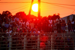PILESGROVE, NJ USA - AUGUST 24, 2024 - The sun sets as some of the sold-out crowd of 5 thousand people stands while singing the National Anthem to start the evening competition at the rodeo. The Cowtown Rodeo is the oldest weekly rodeo in the country.