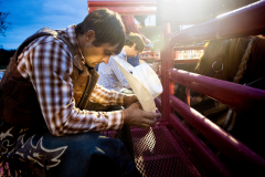 PILESGROVE, NJ USA - AUGUST 31, 2024 -  Before the start of the competition, Cowboy Ray Hostetler prays for his and other cowboys’ safety while behind the bucking shoots before the start of the rodeo.