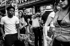 New York, New York, USA- September 14, 2025- A young man young lost in his thoughts at a busy corner in Little Italy during the San Gennaro Festival.