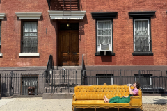 A man drinks bottled water on a hot and humid July afternoon as he waits for moving men to arrive. He thought he would be able to carry the couch up four flights to his apartment by himself. He was not correct.