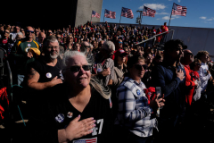 People stand for the national anthem before hearing Republican presidential nominee former President Donald Trump speak during a campaign rally at Dodge County Airport, Sunday, Oct. 6, 2024, in Juneau, Wis.