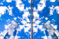 The World Trade Center, and beautiful fluffy crowds. are reflected in a building window creating the impression of twin towers at the site of the 9.11 attacks which toppled both buildings.
