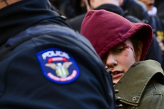 A protestor bleeds from the head as she is arrestedby the NYPD's SRG group while hundreds of protestors clashed with NYPD Officers and ICE Agents in lower Manhattan on November 29, 2025.