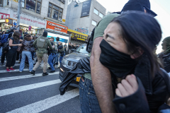 An ICE agent holds a young woman back as she watches on in horror.